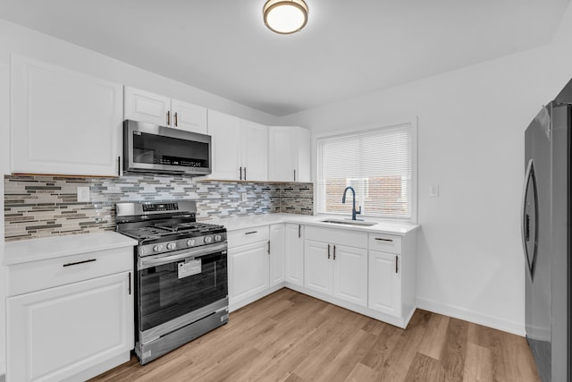 kitchen with light countertops, backsplash, appliances with stainless steel finishes, a sink, and light wood-type flooring