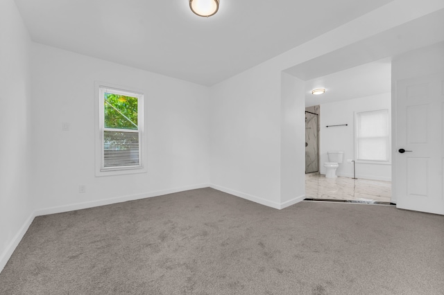 carpeted empty room featuring plenty of natural light and baseboards