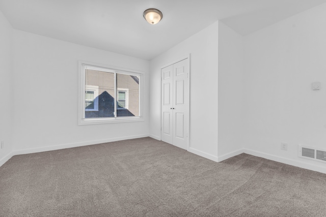 empty room with carpet floors, visible vents, and baseboards