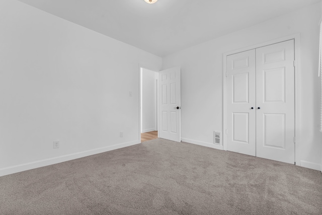 unfurnished bedroom with a closet, carpet flooring, visible vents, and baseboards