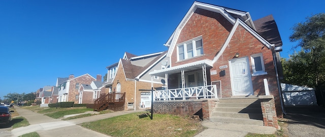 view of front of home with a residential view, covered porch, and brick siding