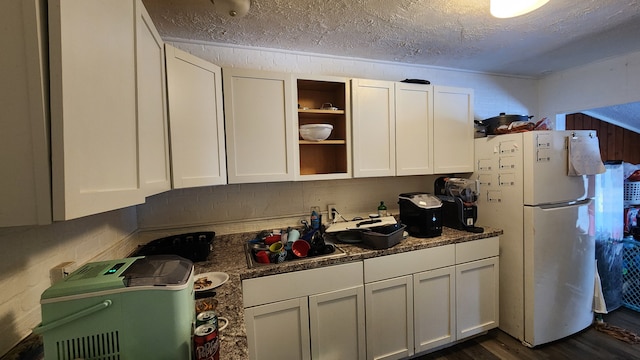 kitchen with freestanding refrigerator, white cabinetry, dark wood finished floors, and a textured ceiling