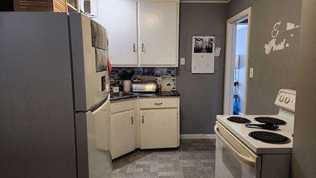 kitchen with dark countertops, white appliances, and white cabinetry