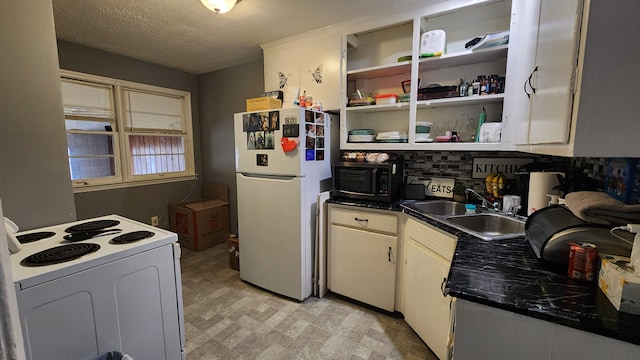 kitchen featuring white appliances, dark countertops, a textured ceiling, light floors, and a sink