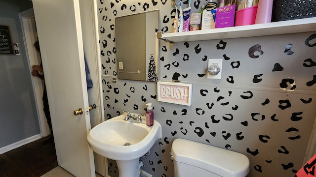 half bath with a sink, toilet, and tile patterned floors