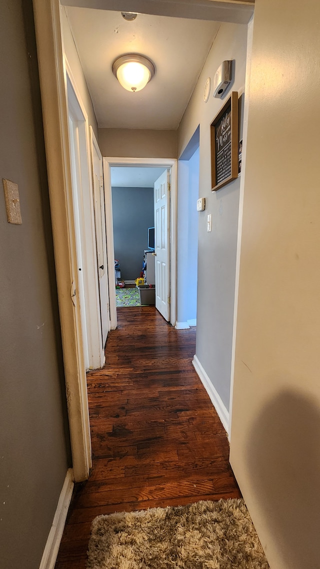 corridor featuring baseboards and wood finished floors