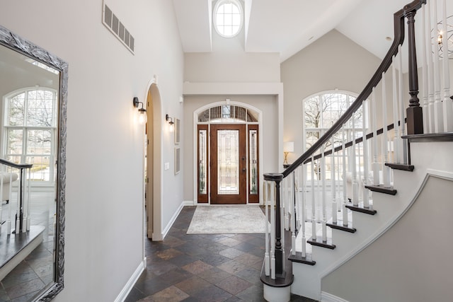 entrance foyer with visible vents, plenty of natural light, baseboards, and stone tile flooring