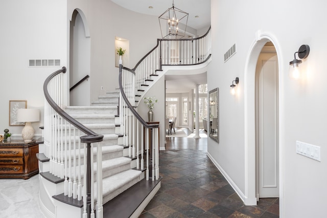 entryway with baseboards, visible vents, arched walkways, and stone tile floors