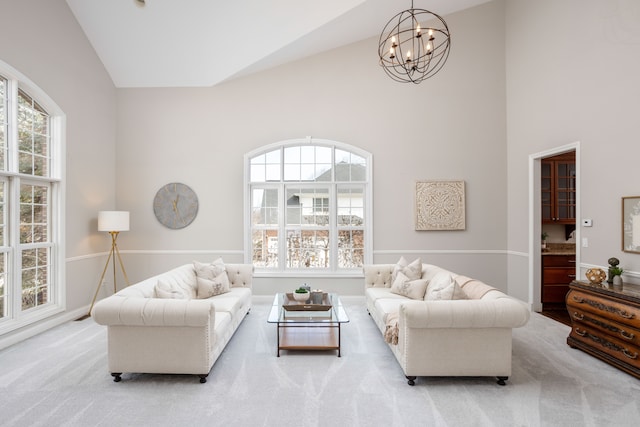 carpeted living room with high vaulted ceiling and an inviting chandelier