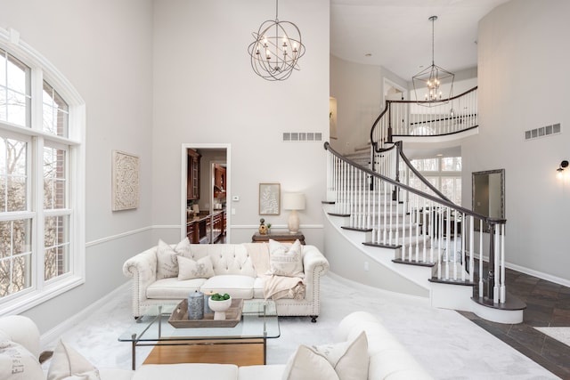 living area with a high ceiling, an inviting chandelier, stairway, and visible vents