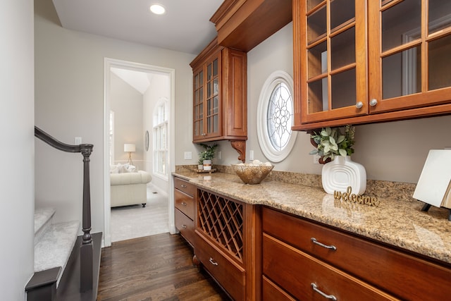 interior space with dark wood finished floors, brown cabinets, glass insert cabinets, and light stone countertops