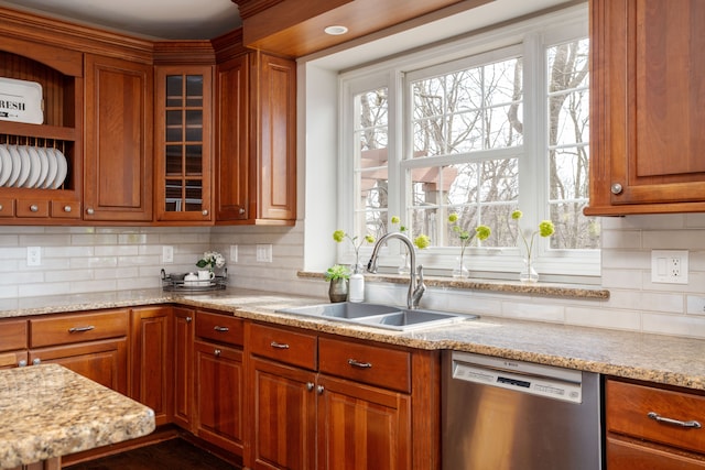 kitchen with brown cabinets, decorative backsplash, a sink, glass insert cabinets, and dishwasher