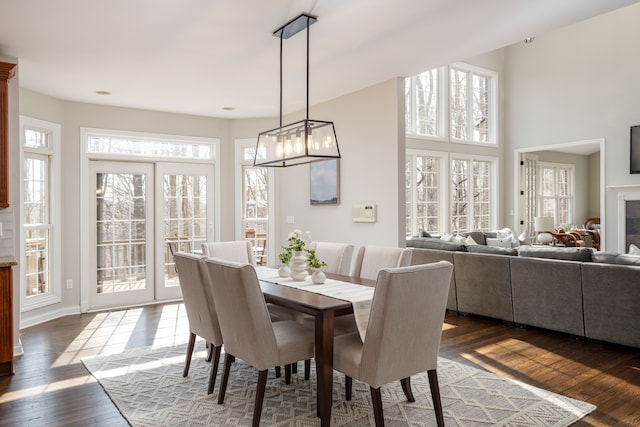 dining space featuring dark wood finished floors, a glass covered fireplace, and baseboards