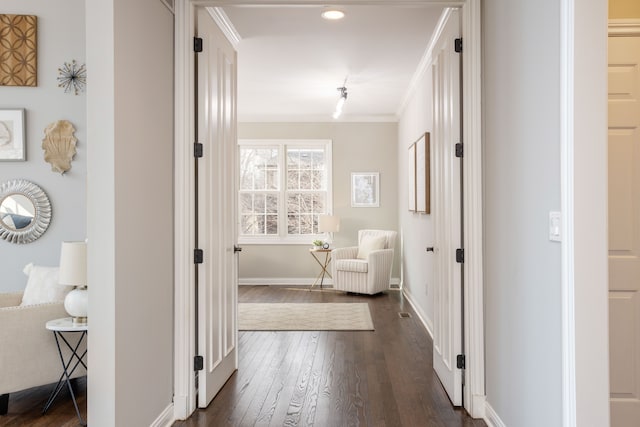 corridor featuring dark wood-type flooring, baseboards, and ornamental molding