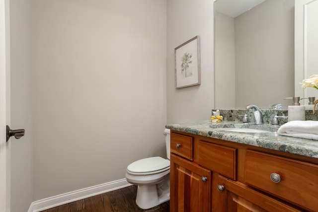 bathroom with baseboards, toilet, wood finished floors, and vanity