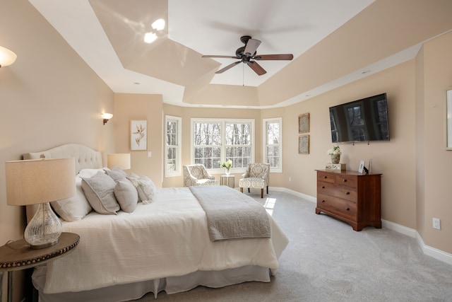 bedroom featuring a ceiling fan, a tray ceiling, light colored carpet, and baseboards