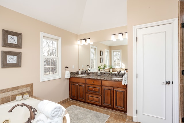 bathroom with double vanity, a sink, a bath, and vaulted ceiling