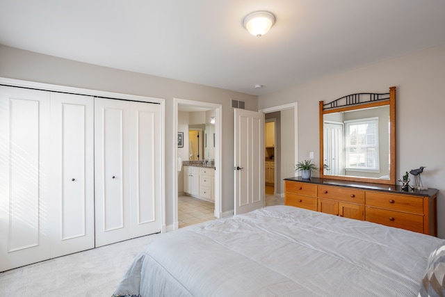 bedroom featuring visible vents, light colored carpet, a closet, and ensuite bath