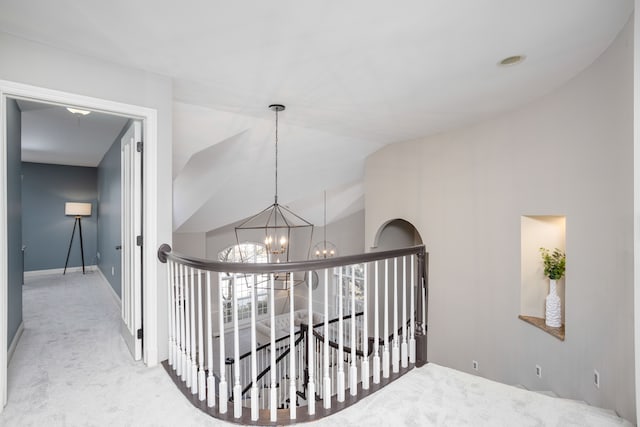 corridor featuring an upstairs landing, a notable chandelier, carpet flooring, and lofted ceiling