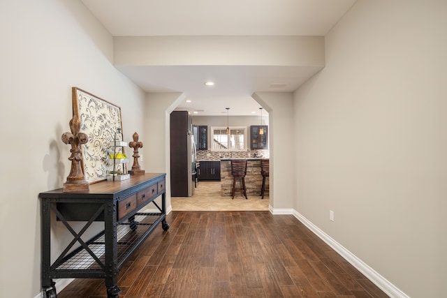 corridor with dark wood finished floors, recessed lighting, and baseboards