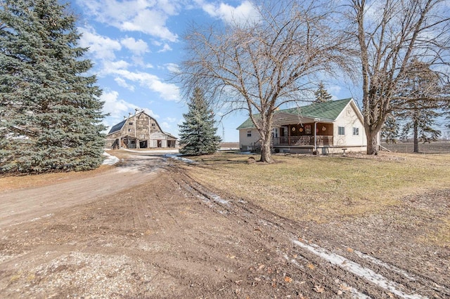 view of front of property with dirt driveway, a porch, and a front yard