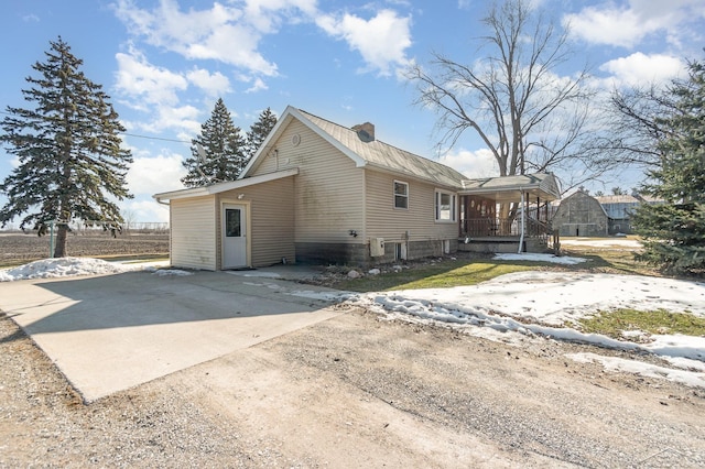 exterior space featuring driveway, covered porch, and a chimney