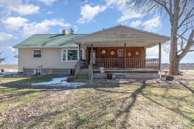 view of front of home featuring a porch, a front yard, metal roof, and a chimney