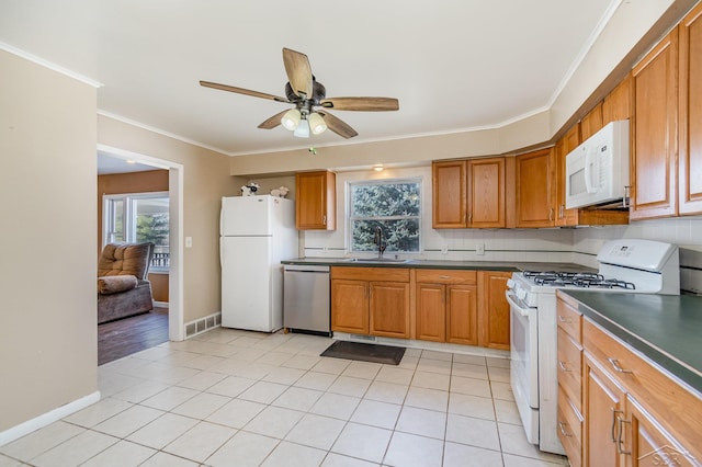 kitchen featuring ornamental molding, a sink, dark countertops, and white appliances