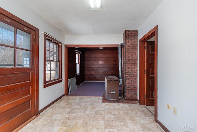 corridor with a textured ceiling and baseboards