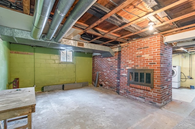 basement featuring concrete block wall, washer / clothes dryer, and a fireplace