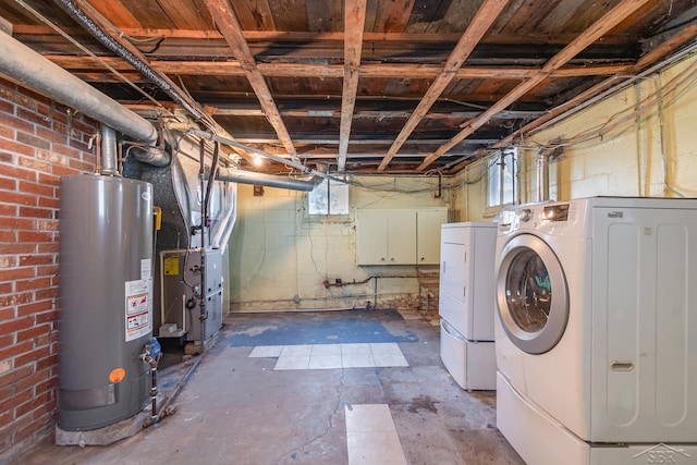 interior space with heating unit, water heater, brick wall, washer and dryer, and laundry area