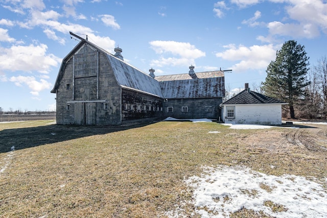 view of side of home with an outdoor structure, a gambrel roof, a barn, a yard, and a chimney