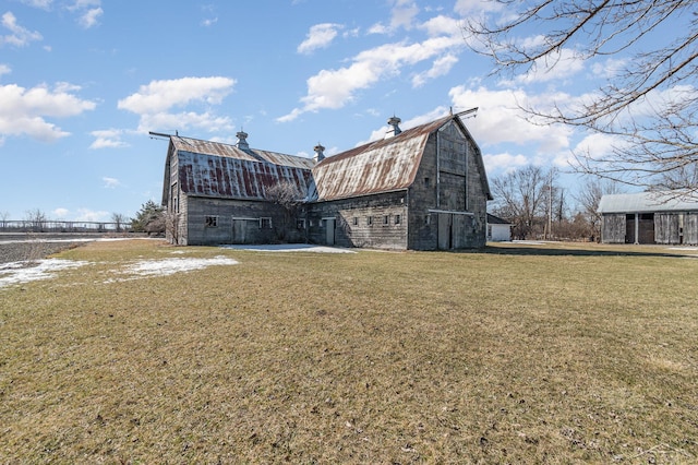 rear view of property featuring a barn, an outdoor structure, and a gambrel roof