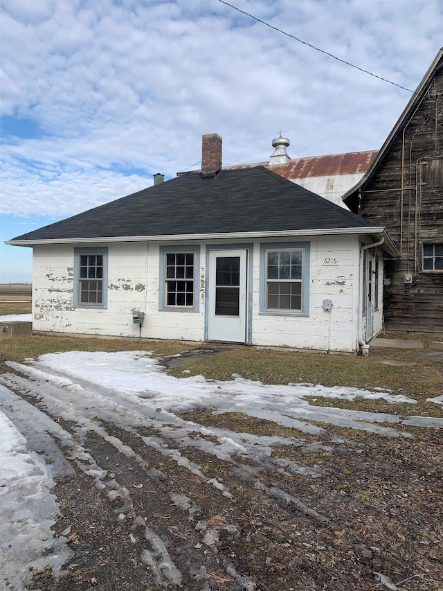 view of front of house featuring a chimney and roof with shingles