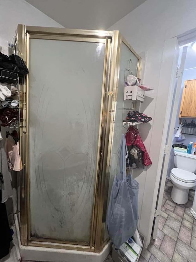 full bathroom with brick floor, a stall shower, and toilet