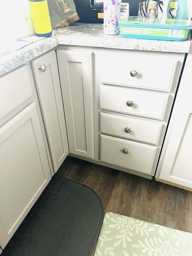 interior details featuring light stone counters, dark wood-style flooring, and white cabinetry