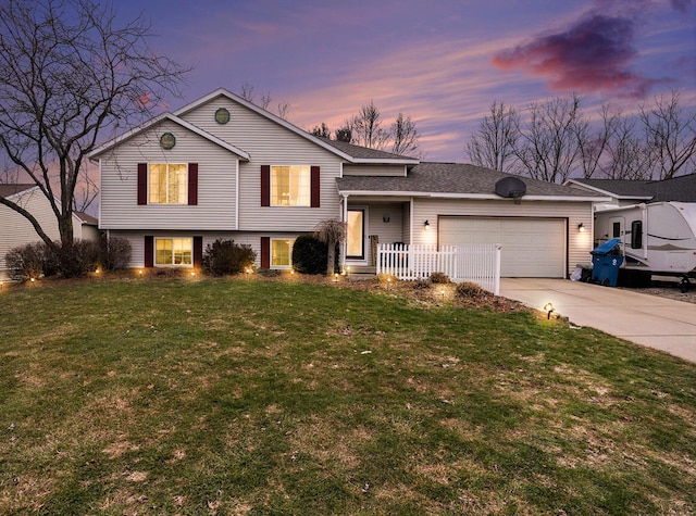 split level home with a garage, driveway, and a front lawn