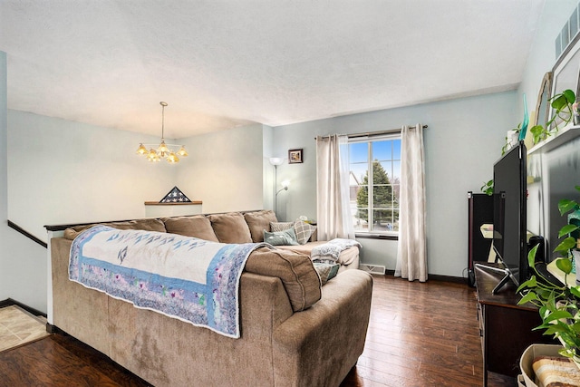 living room with a notable chandelier, visible vents, hardwood / wood-style floors, a textured ceiling, and baseboards