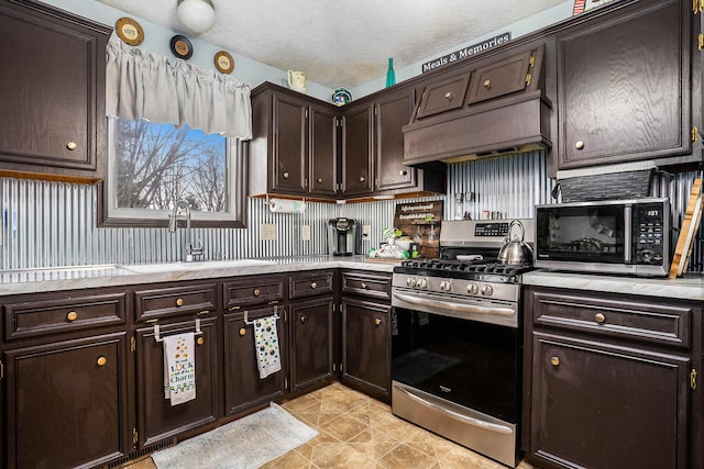 kitchen featuring stainless steel appliances, dark brown cabinets, a textured ceiling, light countertops, and a sink