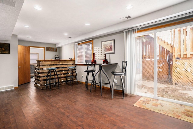 bar featuring visible vents, a bar, and wood finished floors