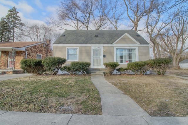 view of front of home with a shingled roof and a front lawn