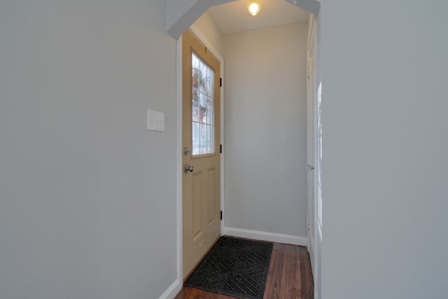 doorway with dark wood-type flooring and baseboards