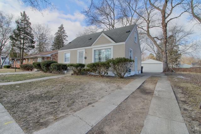 view of front of house featuring an outbuilding, a shingled roof, a detached garage, and fence