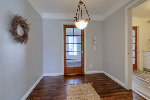 doorway featuring baseboards and wood finished floors