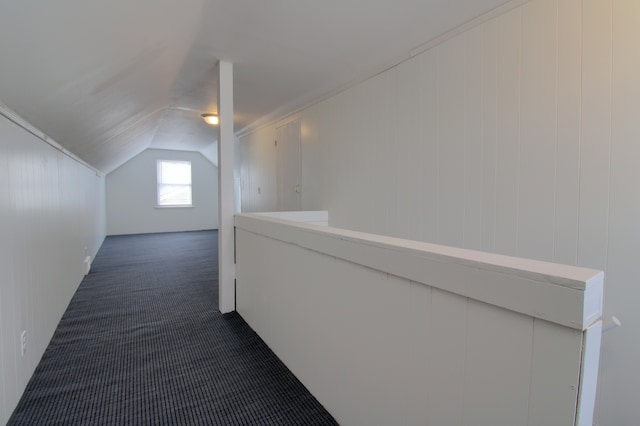 corridor with dark colored carpet and lofted ceiling