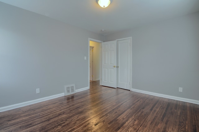 spare room with dark wood-style floors, baseboards, and visible vents