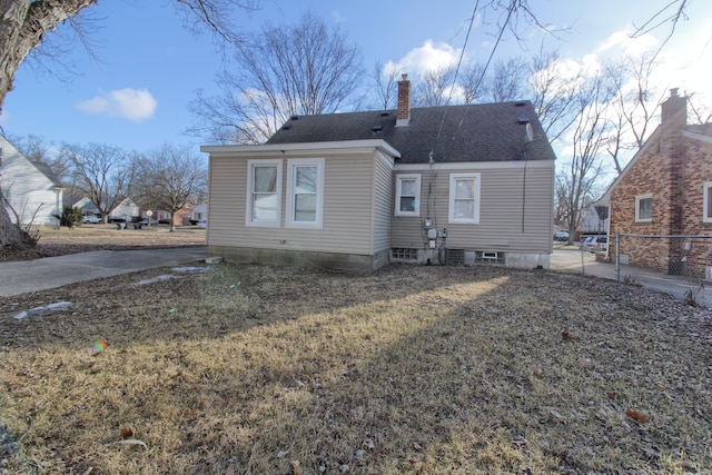 back of property featuring a chimney, fence, a lawn, and roof with shingles