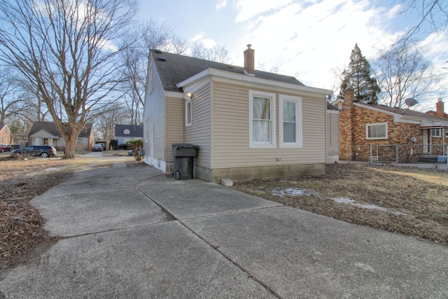 view of property exterior with a shingled roof and a chimney