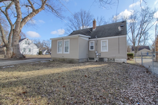 back of house with a shingled roof, a chimney, and fence