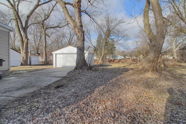 view of yard with an outdoor structure, driveway, and a detached garage